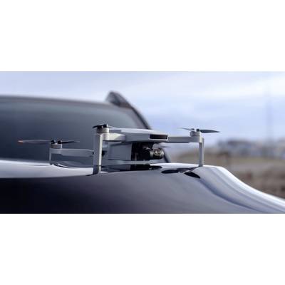 Un drone est posé sur le capot d'une voiture élégante dans un décor extérieur flou, évoquant des thèmes de technologie avancée ou de transport.