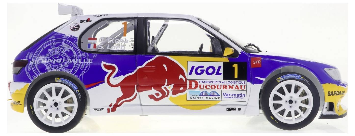 Une voiture miniature avec des autocollants de course colorés, comprenant un logo Red Bull, le numéro '1', et divers noms de sponsors sur ses côtés.