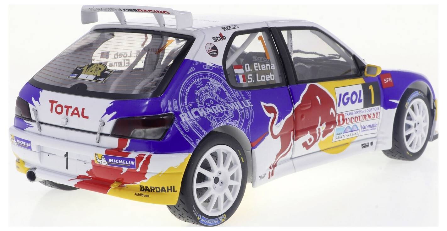 Une voiture de rallye miniature aux couleurs vives avec des logos tels que 'Red Bull' et 'Total'. Le numéro de la voiture est '1', et les noms des pilotes sont inscrits sur les vitres.