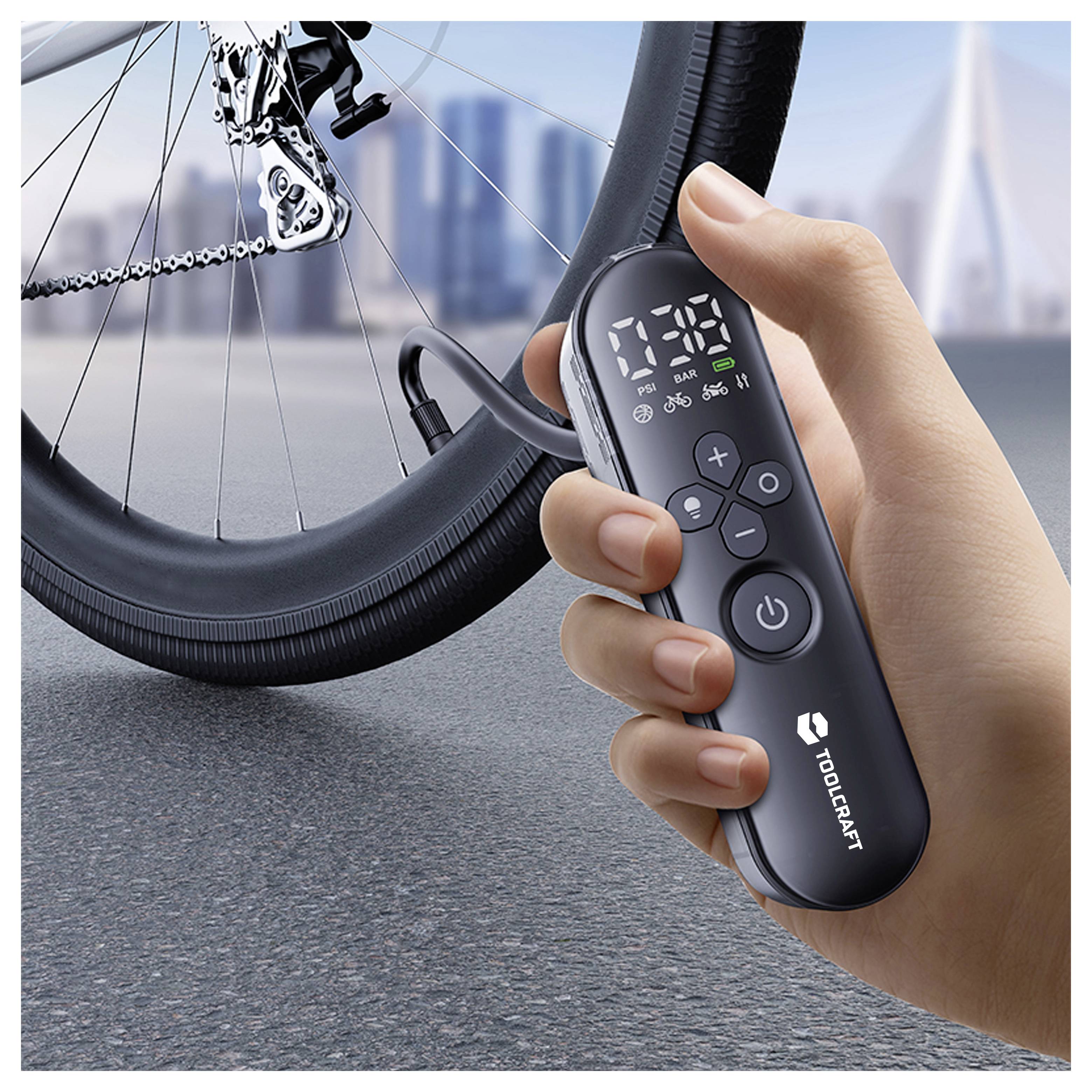 Main tenant une pompe à vélo électrique TOOPCRAFT avec affichage numérique de la pression à côté d'une roue de vélo et d'une valve.