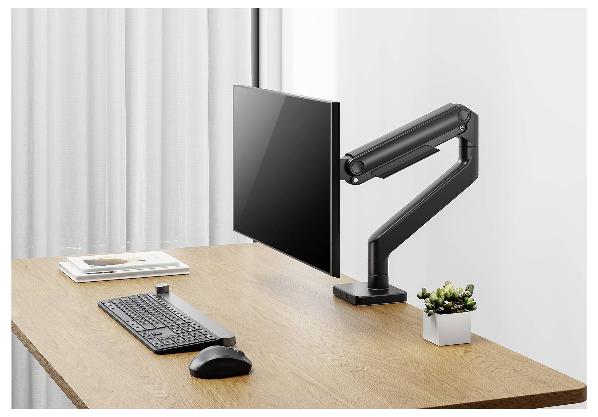 Un écran d'ordinateur monté sur un bras réglable, posé sur un bureau en bois aux côtés d'un clavier, d'une souris et d'une petite plante en pot.