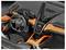 L'image montre l'intérieur d'une voiture de luxe avec un volant portant un logo et une console centrale équipée d'écrans numériques et de commandes.