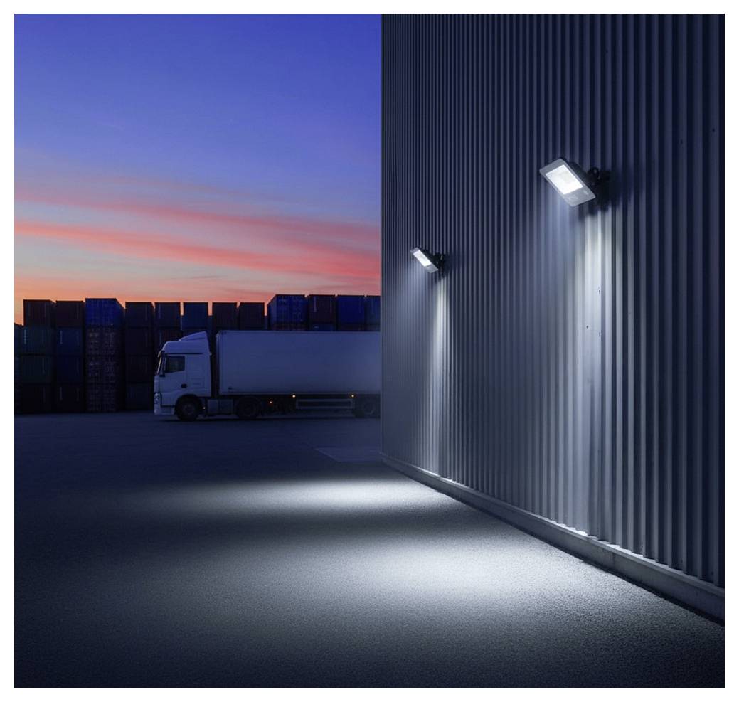 Un camion stationné à côté d'un entrepôt au crépuscule, éclairé par des lumières extérieures. Des conteneurs d'expédition sont visibles en arrière-plan.
