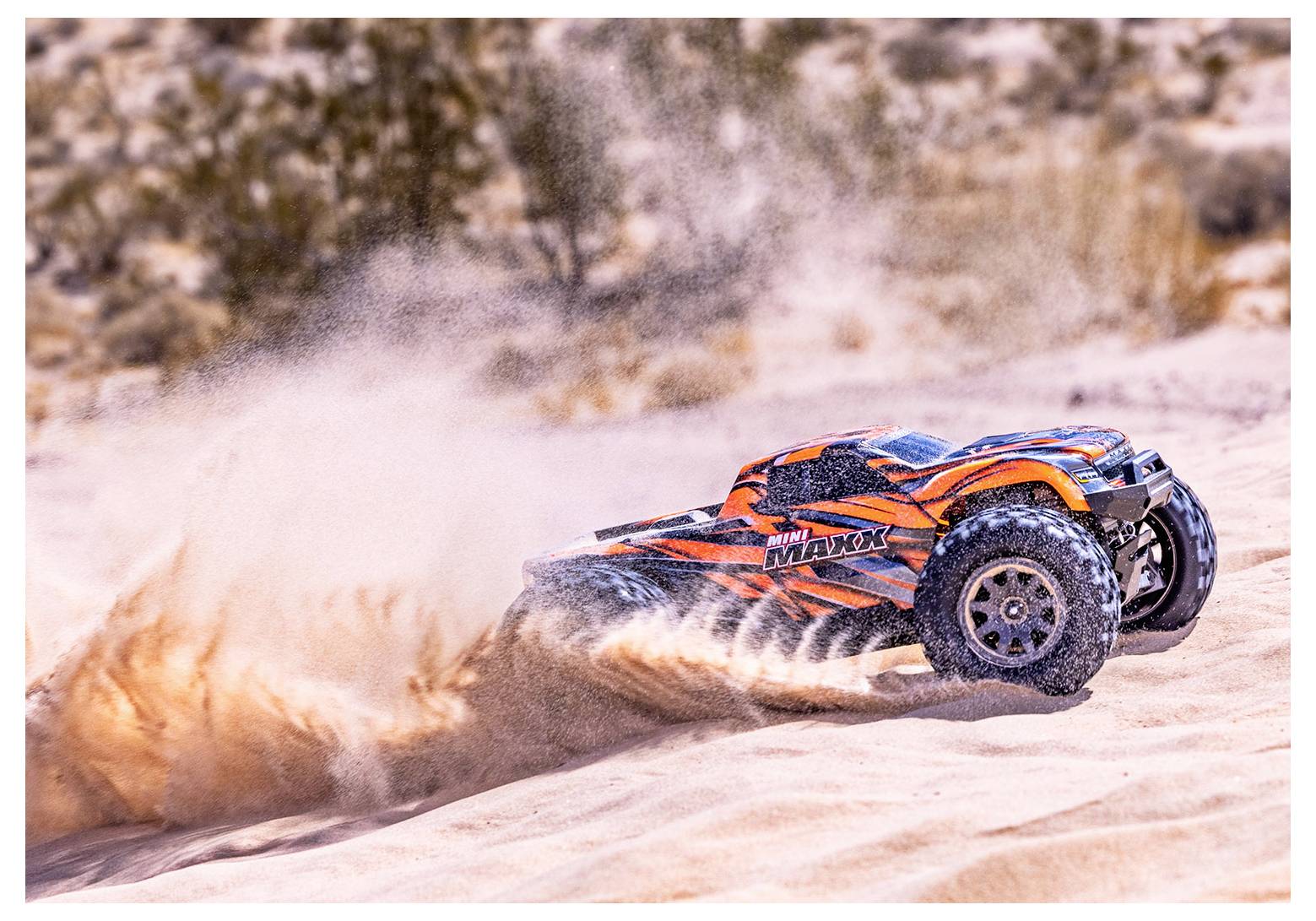 Une voiture télécommandée aux rayures orange et noires soulève du sable alors qu'elle traverse rapidement un terrain désertique.
