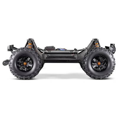 Vue latérale du châssis robuste d'une voiture télécommandée avec de grandes roues tout-terrain, montrant la suspension et les composants électroniques, conçue pour la durabilité.