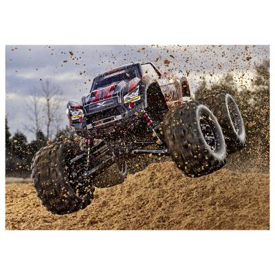 Un monster truck télécommandé s'envole dans les airs sur une piste de terre battue, projetant des débris, avec des arbres flous en arrière-plan.