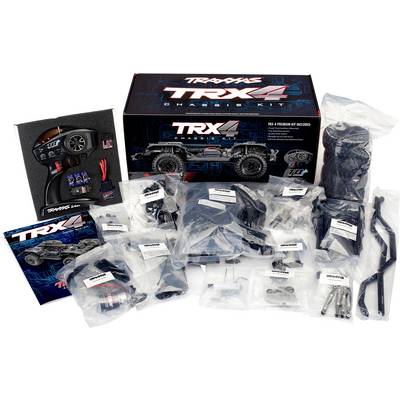 Kit de châssis TRX-4 avec des pièces de véhicule étiquetées, une télécommande et des outils d'assemblage disposés pour construire une voiture télécommandée.