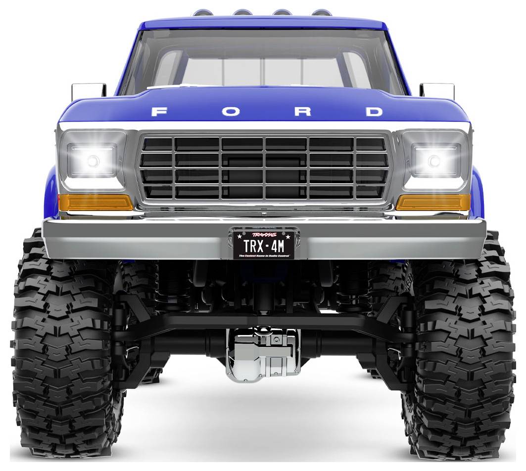 Camionnette Ford bleue avec des pneus robustes et imposants, vue de face. La plaque d'immatriculation affiche 'TRX-4M'.