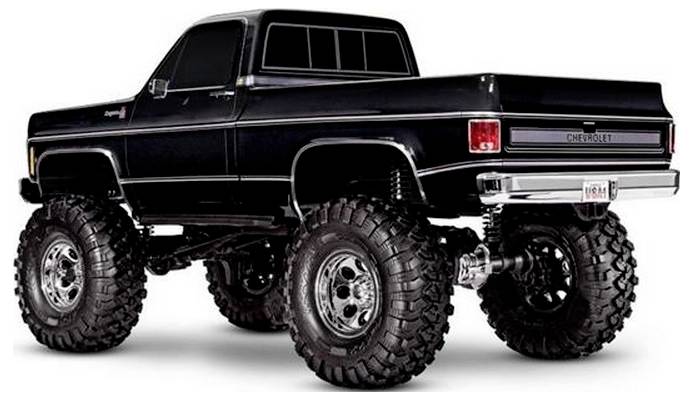 Un pick-up Chevrolet noir surélevé avec de grands pneus tout-terrain, vu sous un angle arrière et latéral.