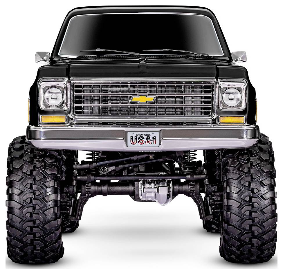 Un camion Chevrolet noir surélevé avec de grandes roues tout-terrain, doté d'une calandre chromée, du logo Chevy et d'une plaque d'immatriculation 'USA-1'.