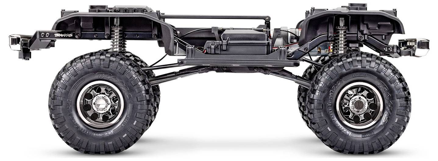 Vue latérale d'un châssis de véhicule tout-terrain avec de grandes roues robustes, suspension apparente et composants de transmission visibles.