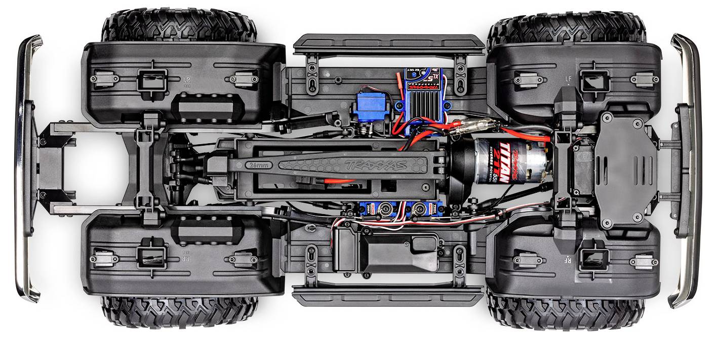 Vue de dessus du châssis d'une voiture télécommandée, montrant des composants comme le moteur, le câblage et quatre grandes roues en caoutchouc, mettant l'accent sur le design et la structure.