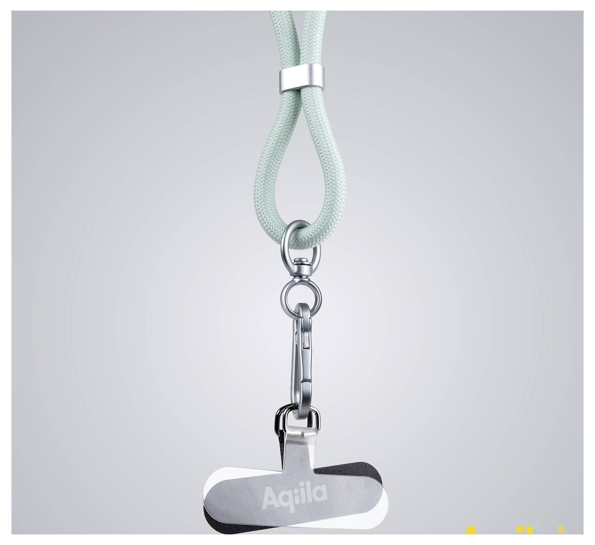 Un lanyard vert menthe avec un clip métallique et un badge nominatif portant le nom 'Aqiila' pend sur un fond gris.