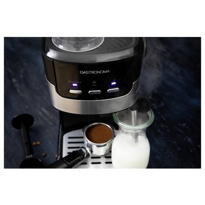 Machine à café 'Gastronoma' sur un comptoir avec du lait vapeur dans une bouteille en verre et un porte-filtre rempli de café moulu.