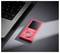 Un lecteur MP3 rouge portant l'étiquette « Intenso » repose sur une surface sombre à côté d'un clavier d'ordinateur portable, éclairé par une lumière douce.