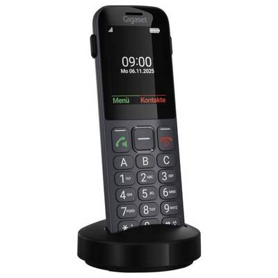 Un téléphone sans fil avec de grands boutons et un affichage montrant l'heure '09:00' et la date 'Lu 06.11.2025', posé sur une base de chargement.