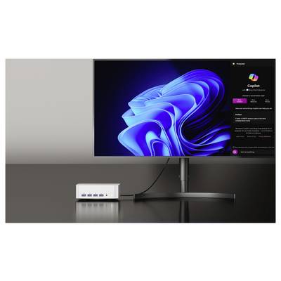 Un écran d'ordinateur affiche un design abstrait lumineux bleu, ressemblant à une interface Windows, à côté d'un concentrateur informatique avec plusieurs ports USB.