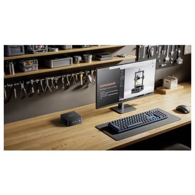 Un bureau avec un écran affichant une page web 'MERGEBOTS', un clavier, une souris et un petit ordinateur. Des étagères en arrière-plan contiennent des outils.