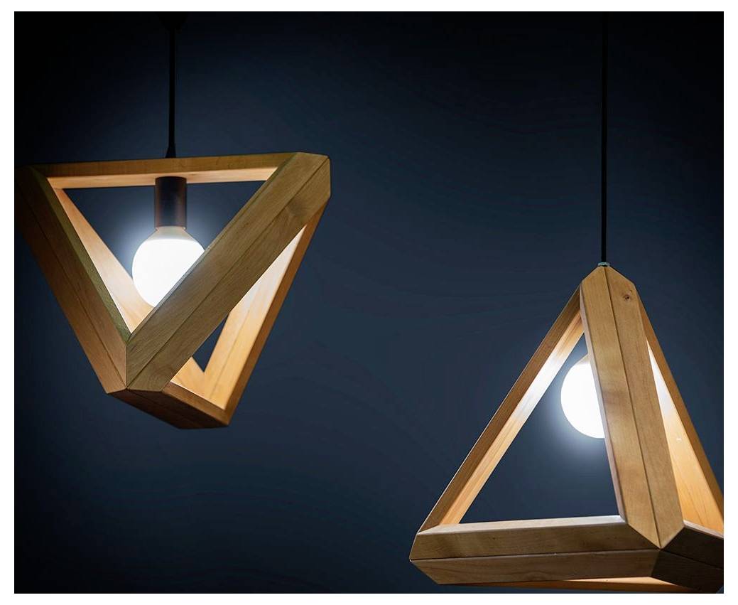 Deux luminaires suspendus triangulaires en bois sur un fond sombre, chacun avec une ampoule centrale lumineuse, offrant une esthétique moderne.