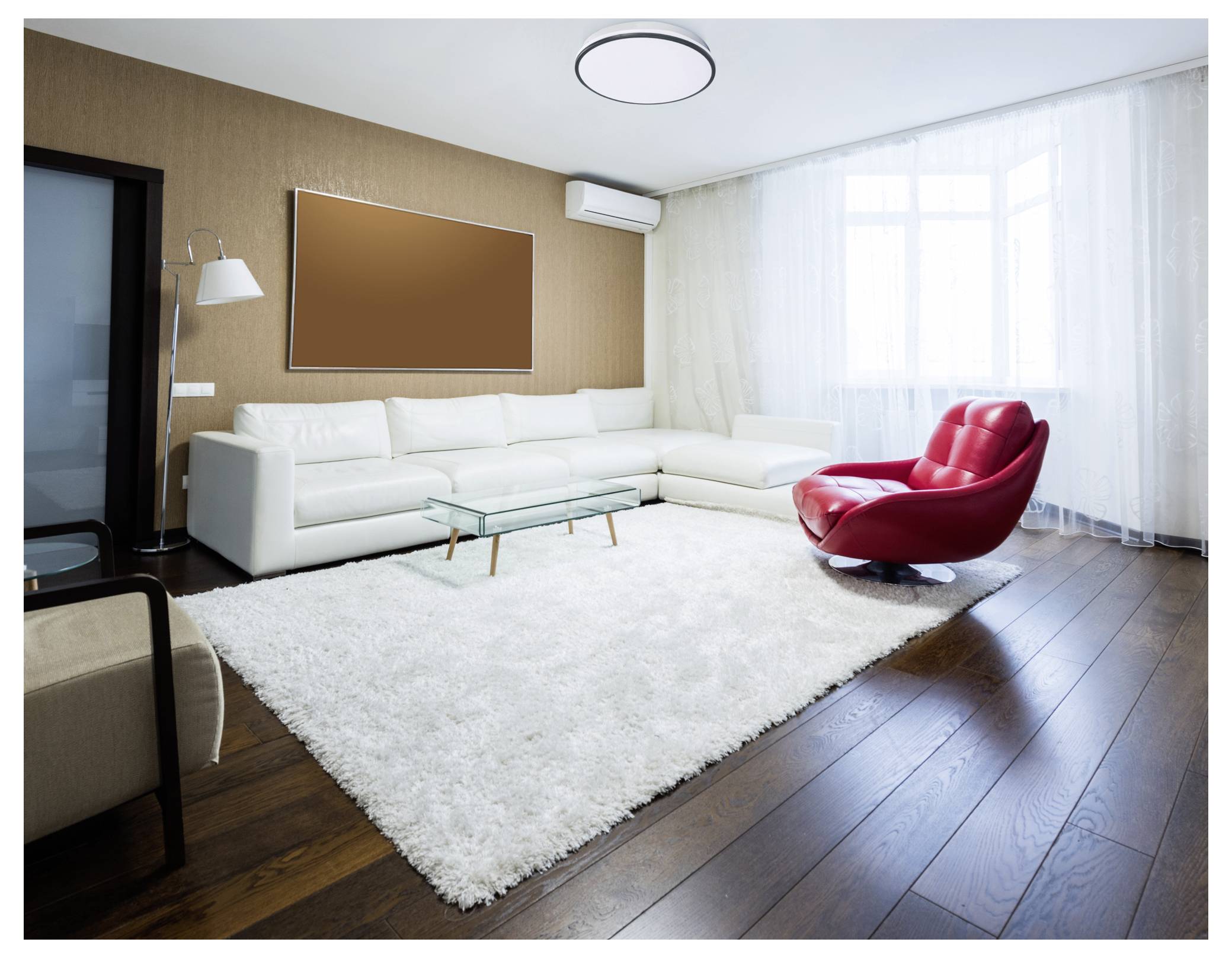 Un salon moderne présente un canapé sectionnel blanc, un fauteuil rouge, une table basse en verre et une grande fenêtre, créant un espace lumineux et accueillant.
