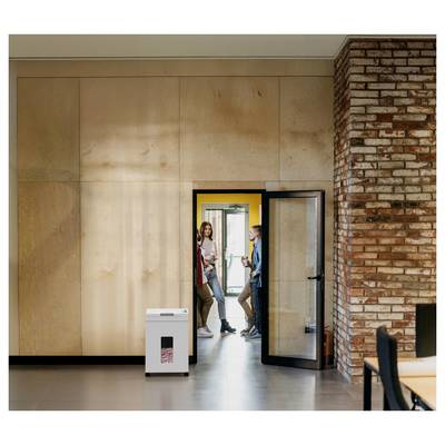 Un petit groupe de personnes discutant de manière décontractée près d'une porte dans un environnement de bureau moderne, avec un mur de briques et des panneaux en bois visibles.