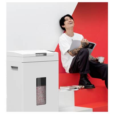 Personne assise sur des marches rouges, tenant une tablette et une tasse, souriant. Destructeur de documents blanc avec des feuilles déchiquetées visibles à proximité.