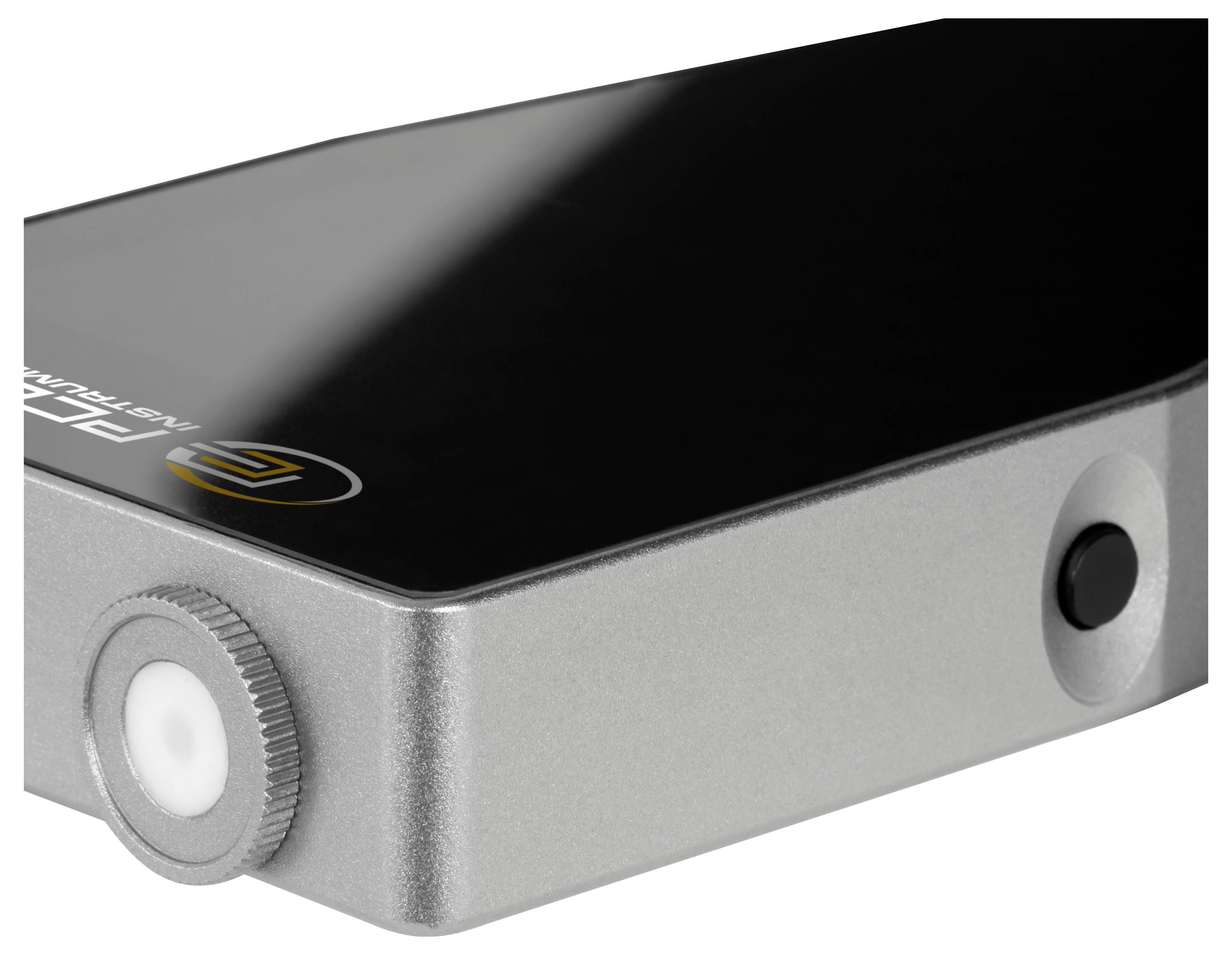 Appareil électronique compact noir et argent avec un bouton rotatif blanc et un bouton latéral, présenté sur un fond blanc.