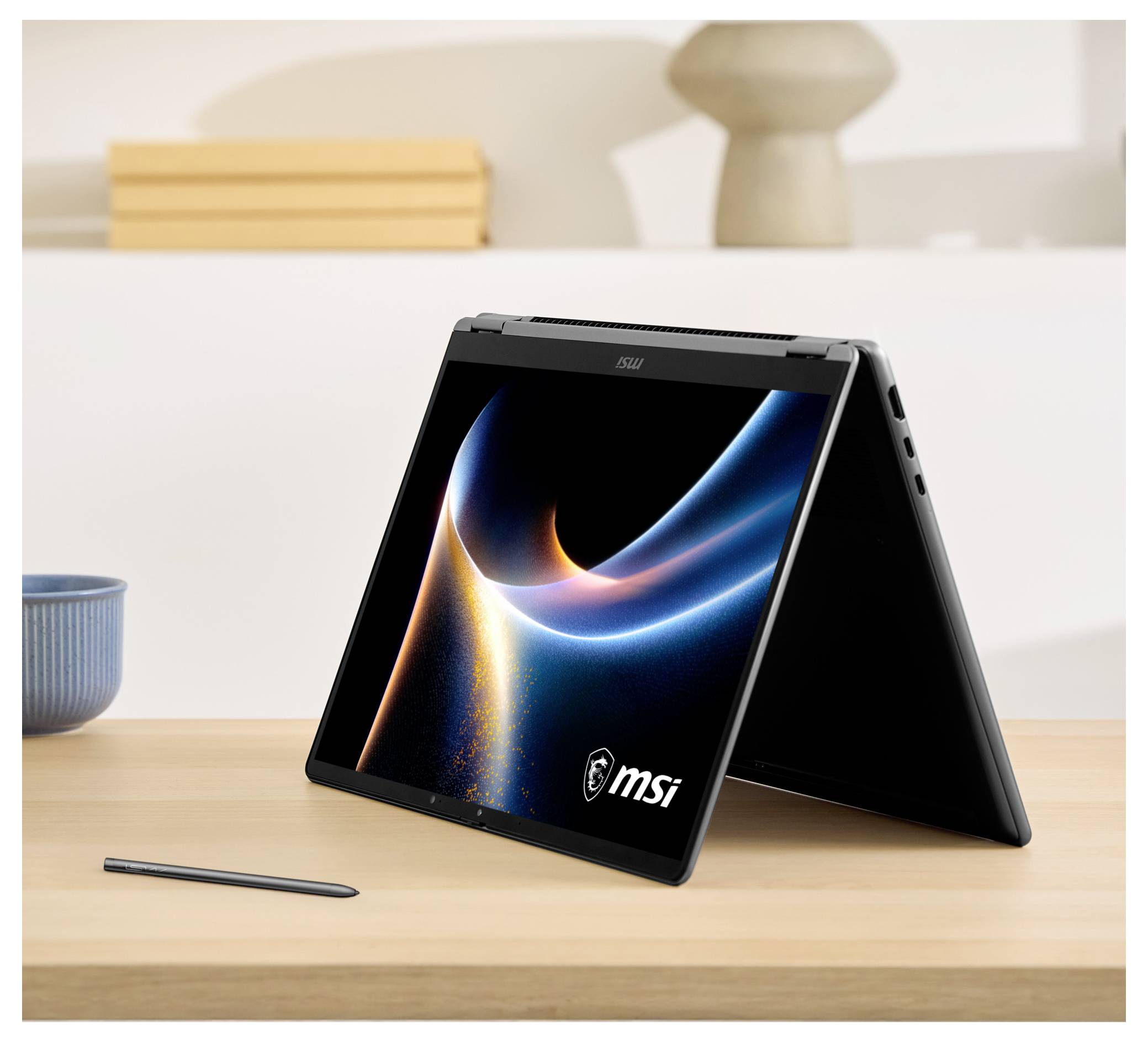 Un ordinateur portable en mode tent sur un bureau avec un stylet à proximité, affichant un design tourbillon dynamique sur l'écran, marqué de la marque « MSI ».