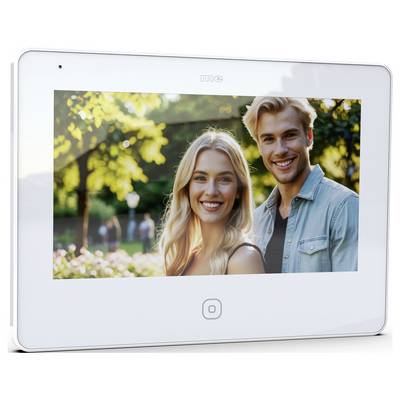 Un homme et une femme souriants dans un parc ensoleillé, entourés d'arbres et de fleurs, suggérant un cadre extérieur agréable.
