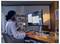 Une personne est assise à un bureau en train de travailler sur un ordinateur, tenant une tasse de café. L'écran affiche un document ouvert dans un espace de travail organisé.