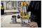 Une personne démontre l'utilisation d'une défonceuse plongeante jaune et noire dans un atelier, affichant la précision et le contrôle dans un environnement de travail du bois.