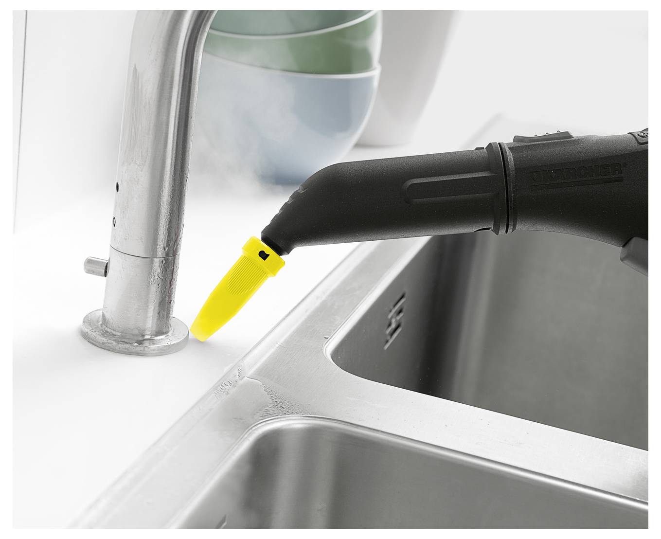 Une main connecte un tuyau d'aspirateur noir et jaune à un outil électrique bleu pour éliminer la poussière pendant l'utilisation.