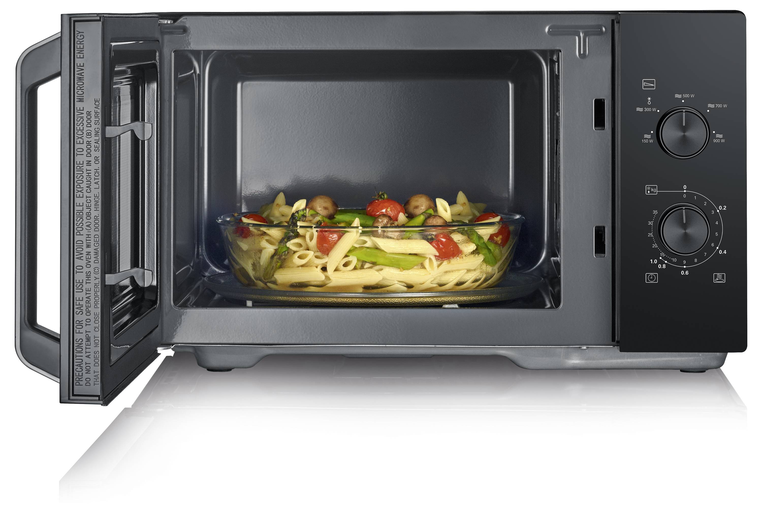 Micro-ondes avec une porte ouverte montrant un plat en verre contenant des pâtes cuites, des tomates et des légumes, indiquant que la nourriture est en cours de réchauffement.