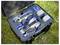 Un étui ouvert sur l'herbe contenant un drone, une télécommande, deux batteries et des accessoires, organisés dans des compartiments en mousse.