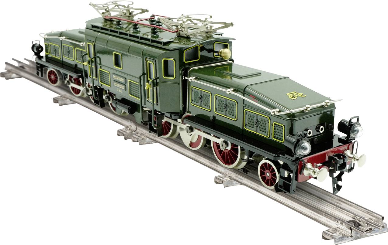 Train miniature sur des rails, mettant en avant un design vintage avec une carrosserie verte et des roues rouges. Les détails incluent des caractéristiques mécaniques complexes.