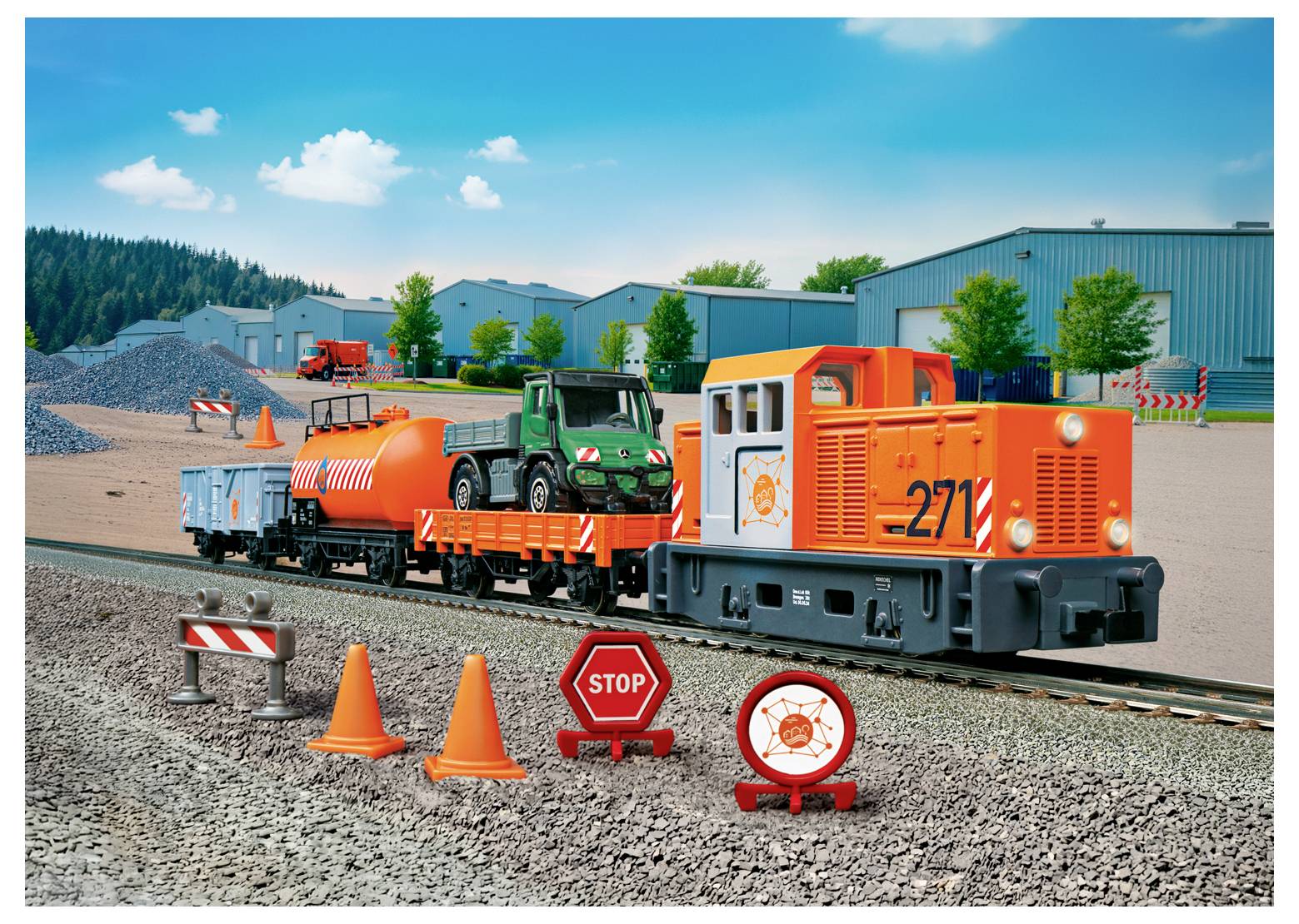 Un train jouet avec une locomotive orange, un wagon plat transportant un véhicule, et un wagon-citerne sur une voie. Des cônes, un panneau d'arrêt et des rochers à proximité.