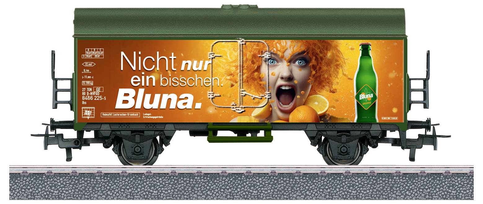 Une voiture de train miniature avec une publicité mettant en scène une personne avec une coiffure orange, tenant des oranges et criant, à côté d'une bouteille verte. Texte : « Ce n'est pas juste un petit peu de Bluna. »