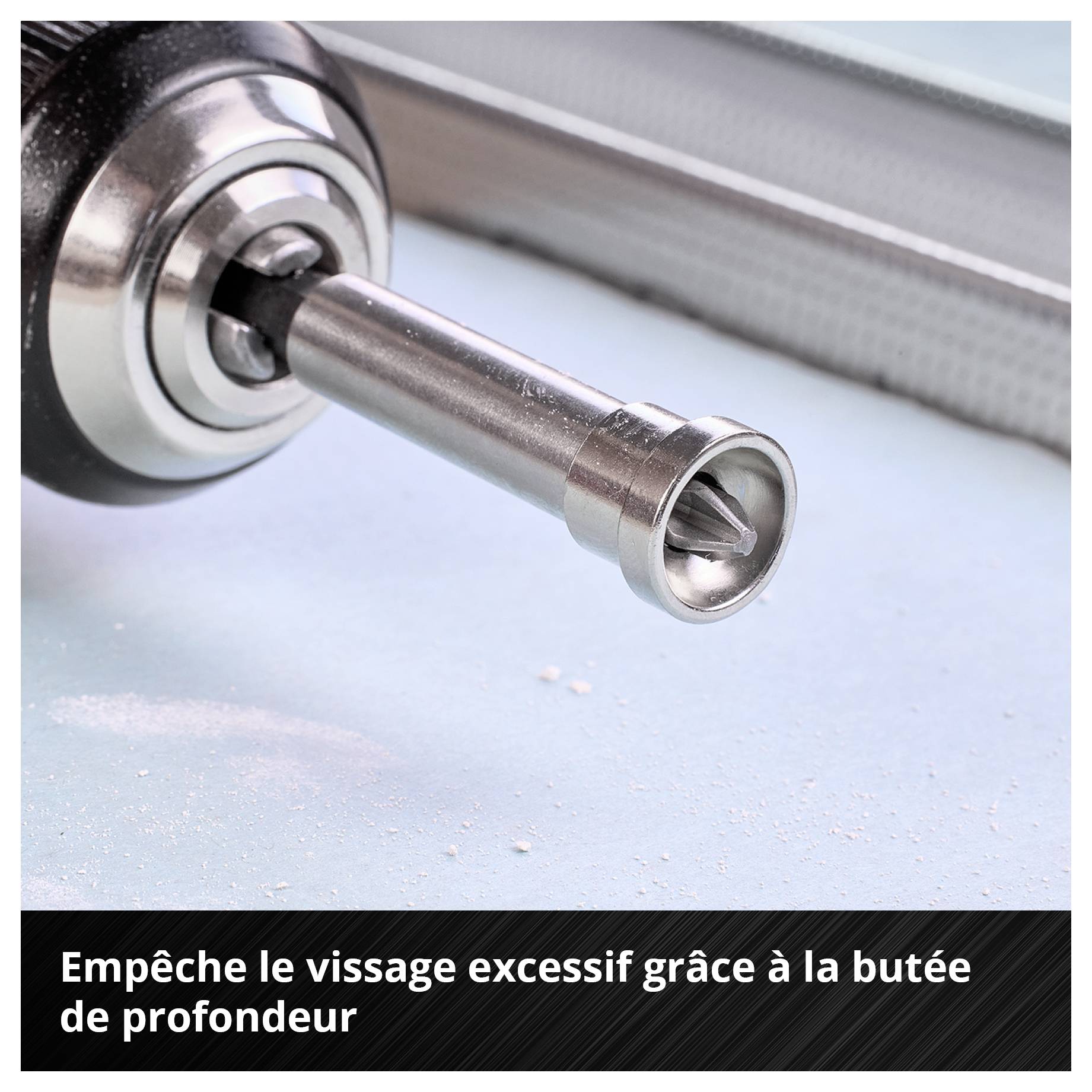 Un limiteur de profondeur sur une tête de forage empêche le surserrage lors du vissage sur une surface bleue, de la poussière visible.