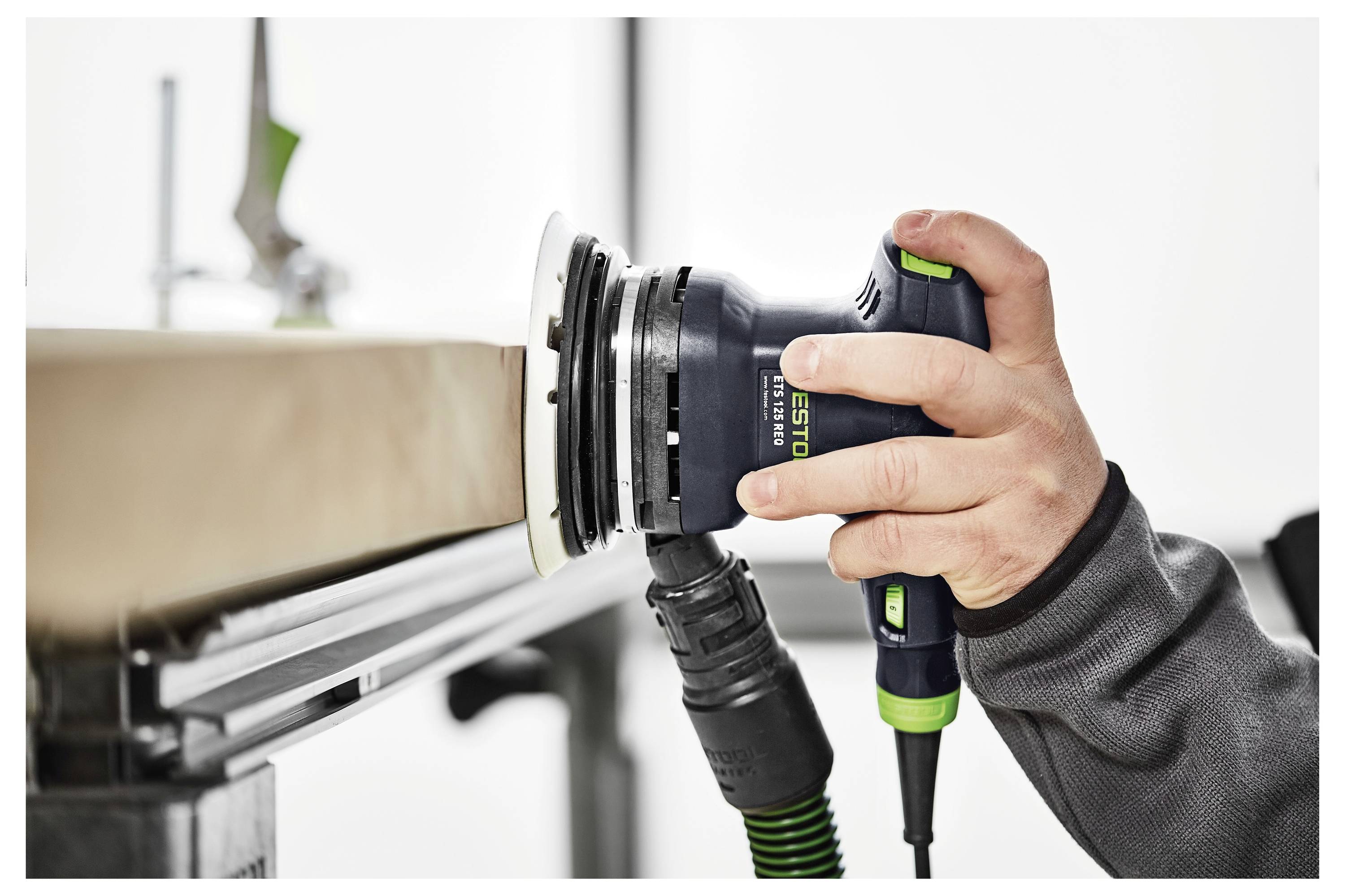 Une personne utilisant une ponceuse électrique pour lisser une surface en bois, mettant en avant un gros plan de l'outil en action, avec un accent sur la précision.