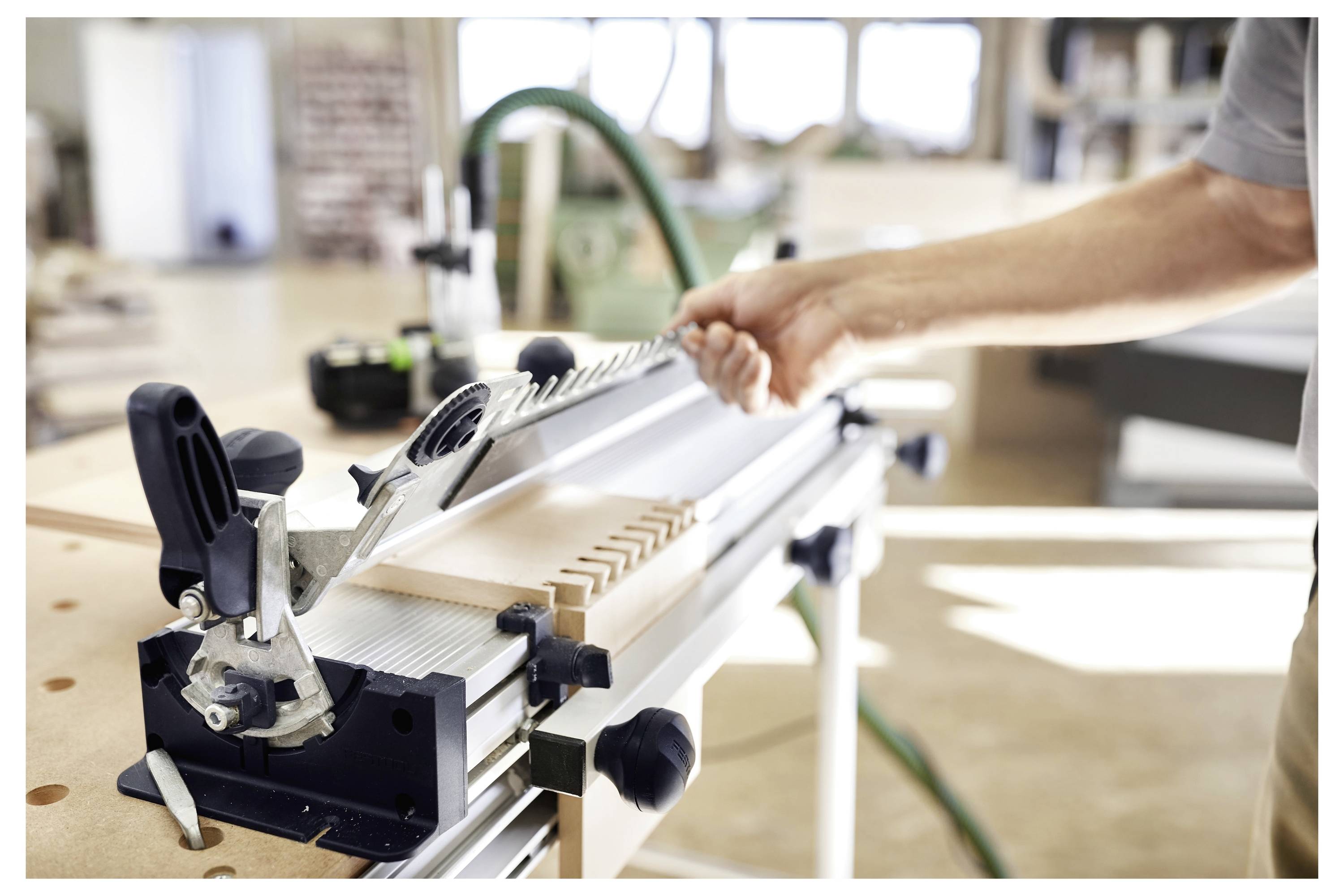 Une personne utilise un outil de menuiserie pour découper des rainures dans un morceau de bois dans un cadre d'atelier, mettant en évidence le savoir-faire du travail du bois.