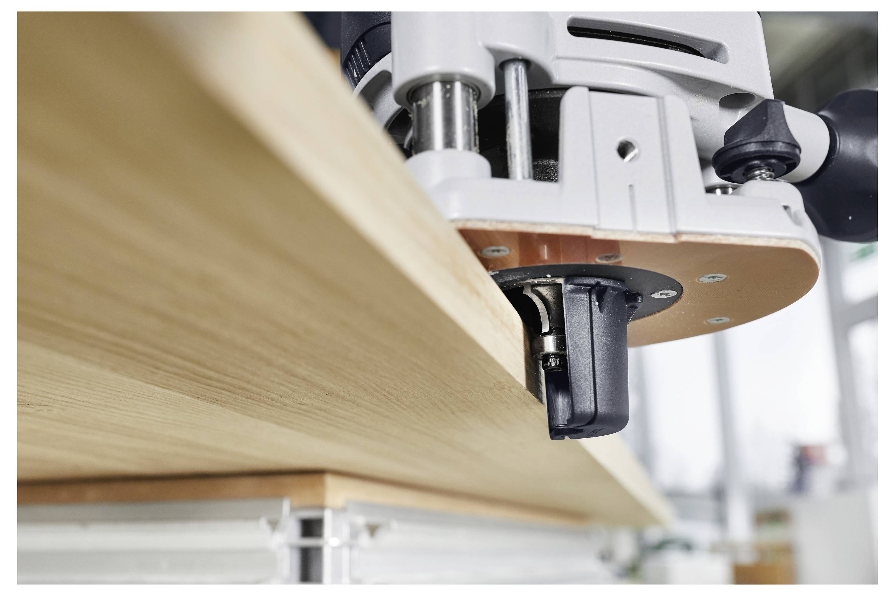 Un gros plan d'un outil électrique qui lisse le bord d'une planche en bois, démontrant l'ébénisterie de précision dans un environnement d'atelier lumineux.