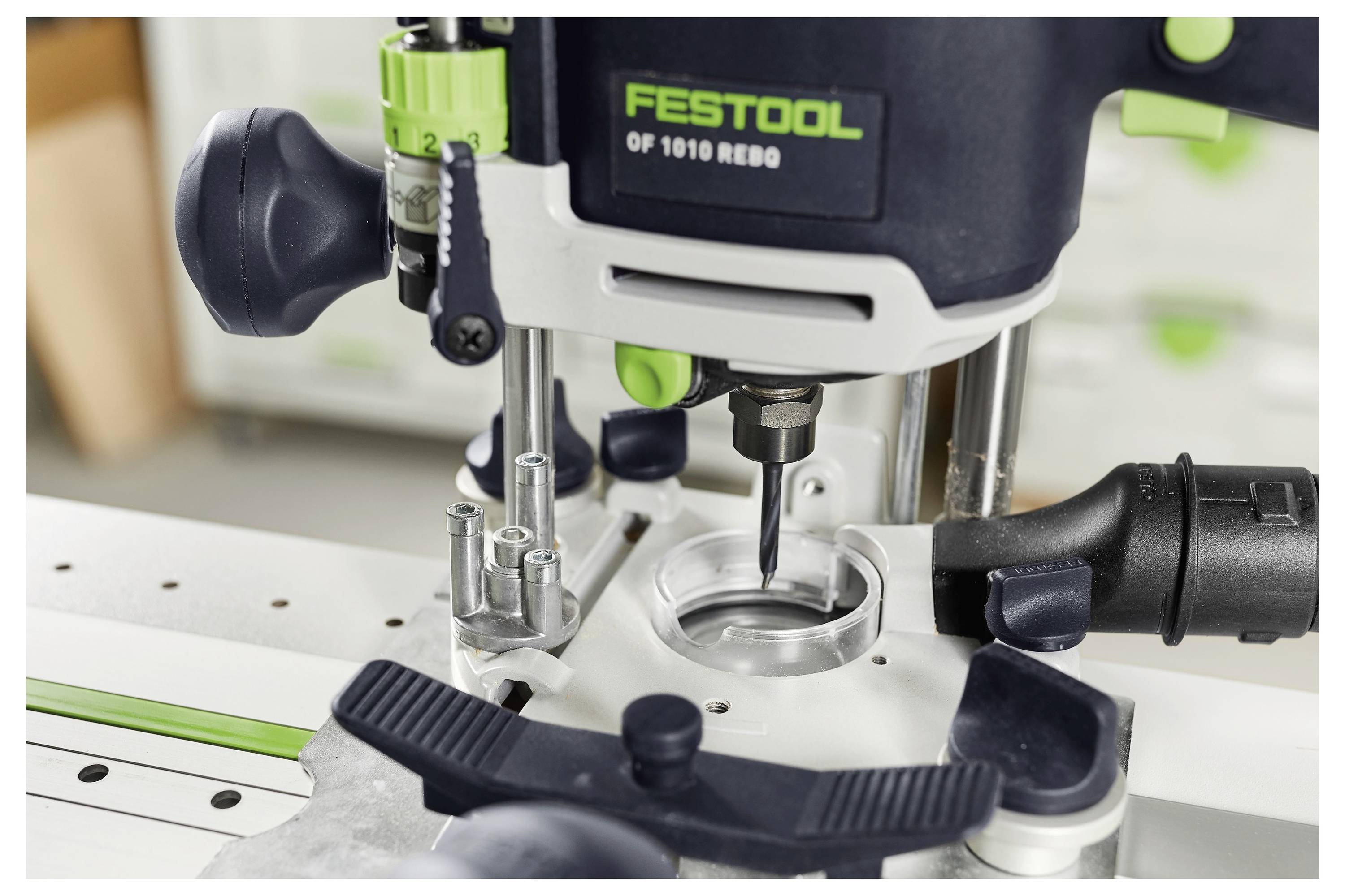 Défonceuse Festool OF 1010 REBQ en utilisation sur un établi, montrant une coupe de précision avec une visibilité claire des commandes et du cadran d'ajustement de profondeur.