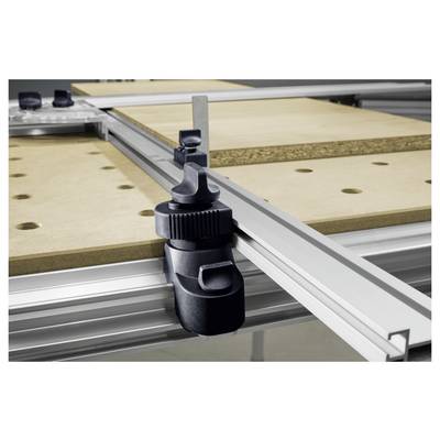 Un gros plan d'un serre-joint en métal maintenant fermement une planche en bois sur un établi, avec des règles et des rails de guidage en arrière-plan, indiquant un configuration de mesure précise.