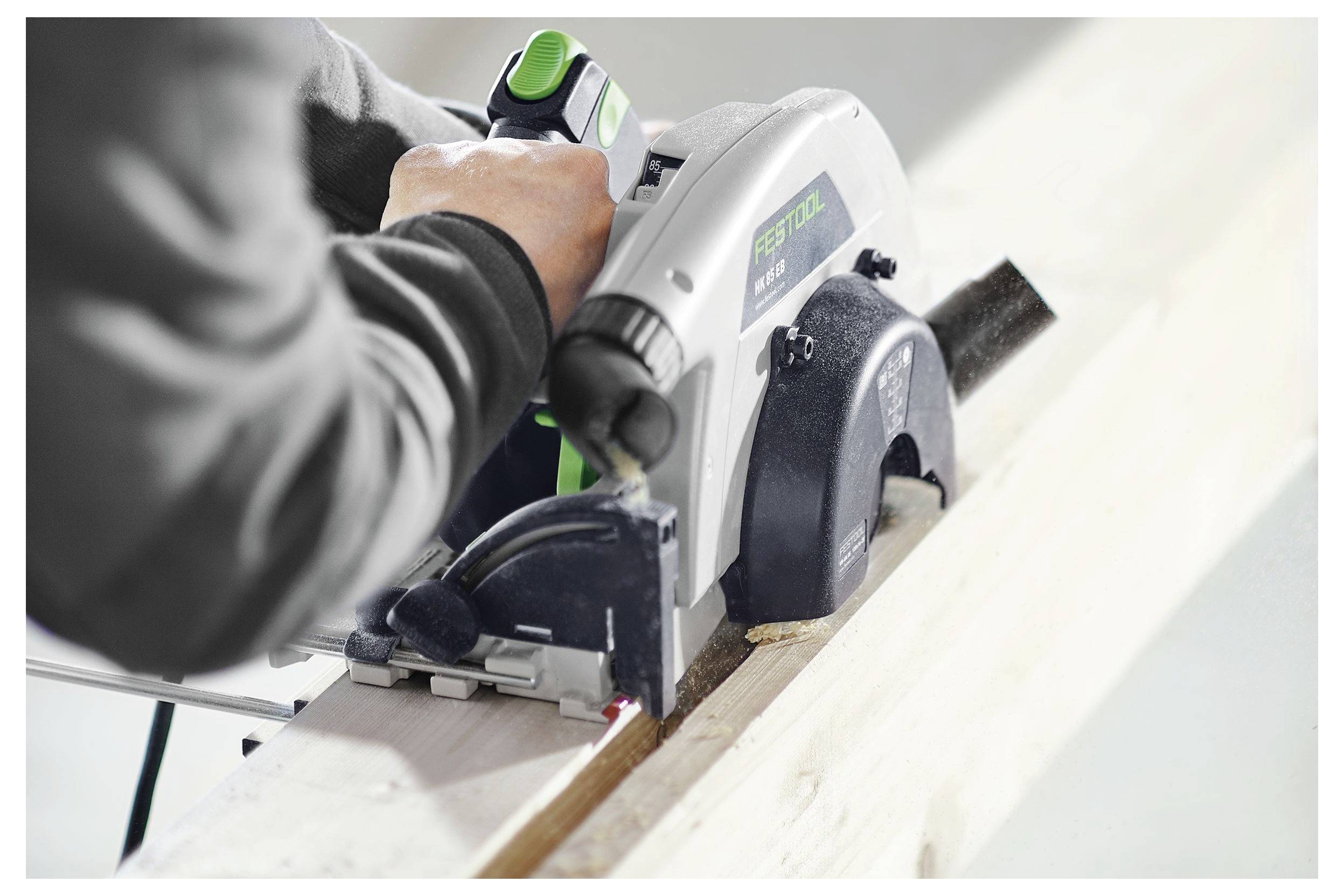 Un travailleur utilise une scie circulaire électrique portative pour découper une planche de bois, en se concentrant sur la précision et la sécurité dans un atelier.