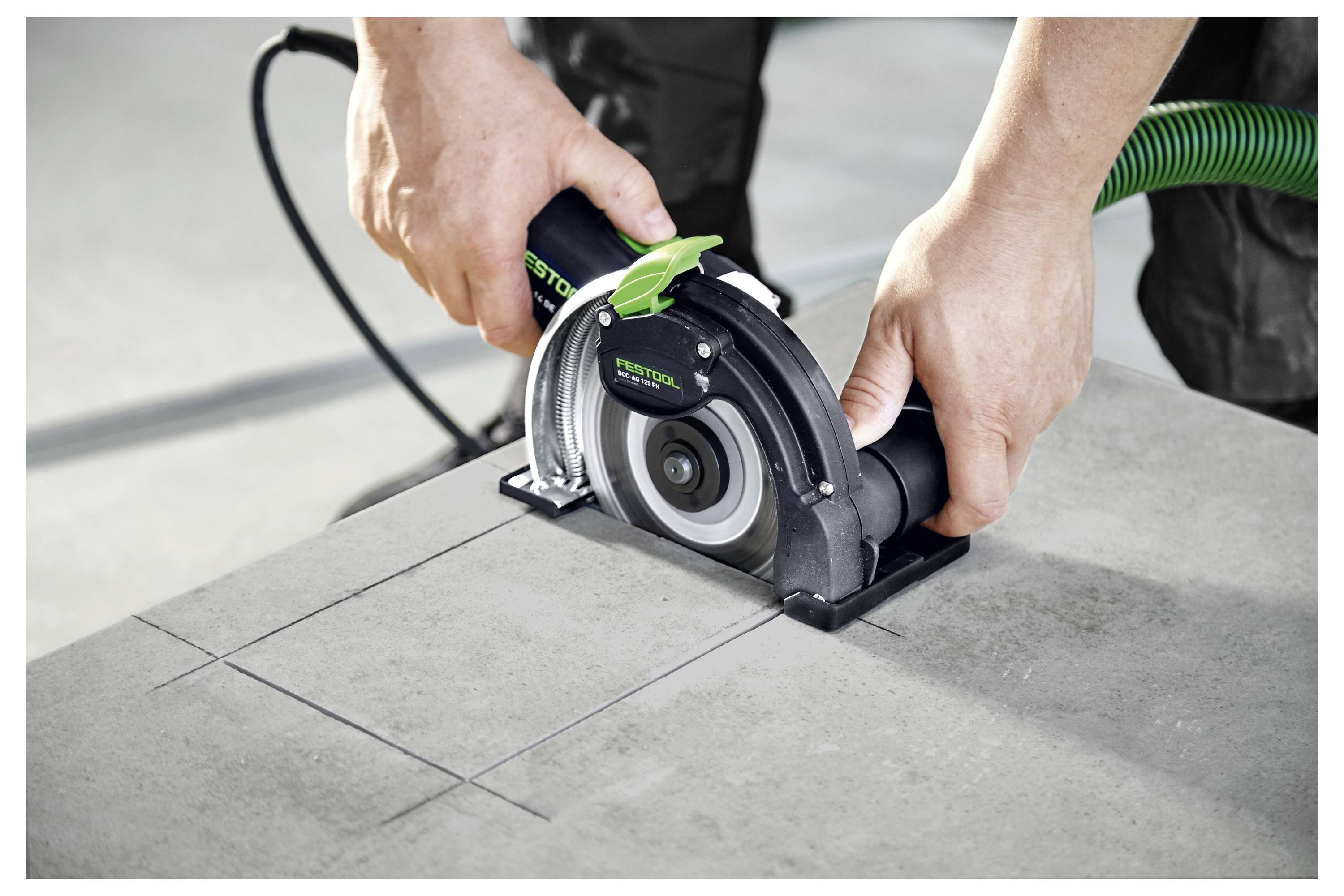 « Une paire de mains actionne un outil électrique pour tracer une ligne droite dans une dalle de béton. L'outil est relié à un tuyau vert. »
