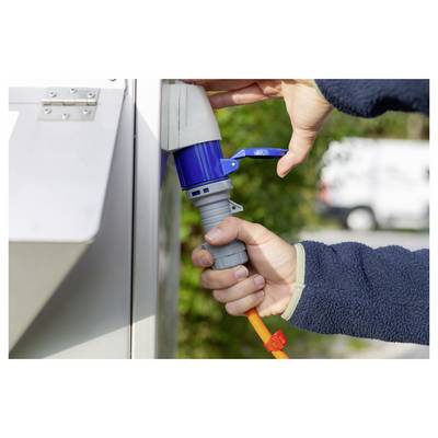 Les mains branchent un câble d'alimentation orange dans une prise électrique bleue extérieure sur un boîtier d'utilité.
