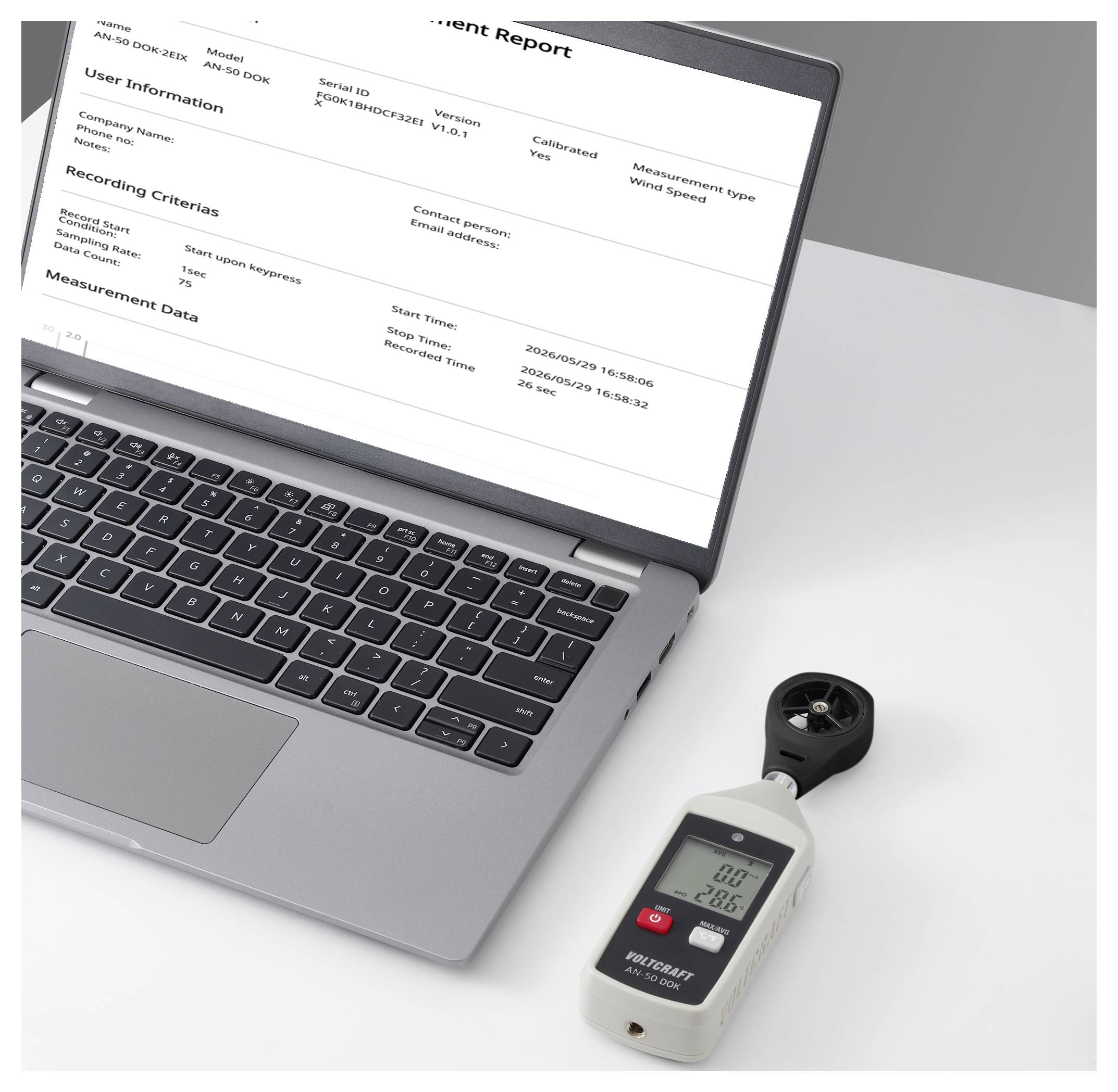 Un ordinateur portable affichant un « Rapport de Mesure » à côté d'un anémomètre portatif sur un bureau, suggérant une collecte ou une analyse de données.