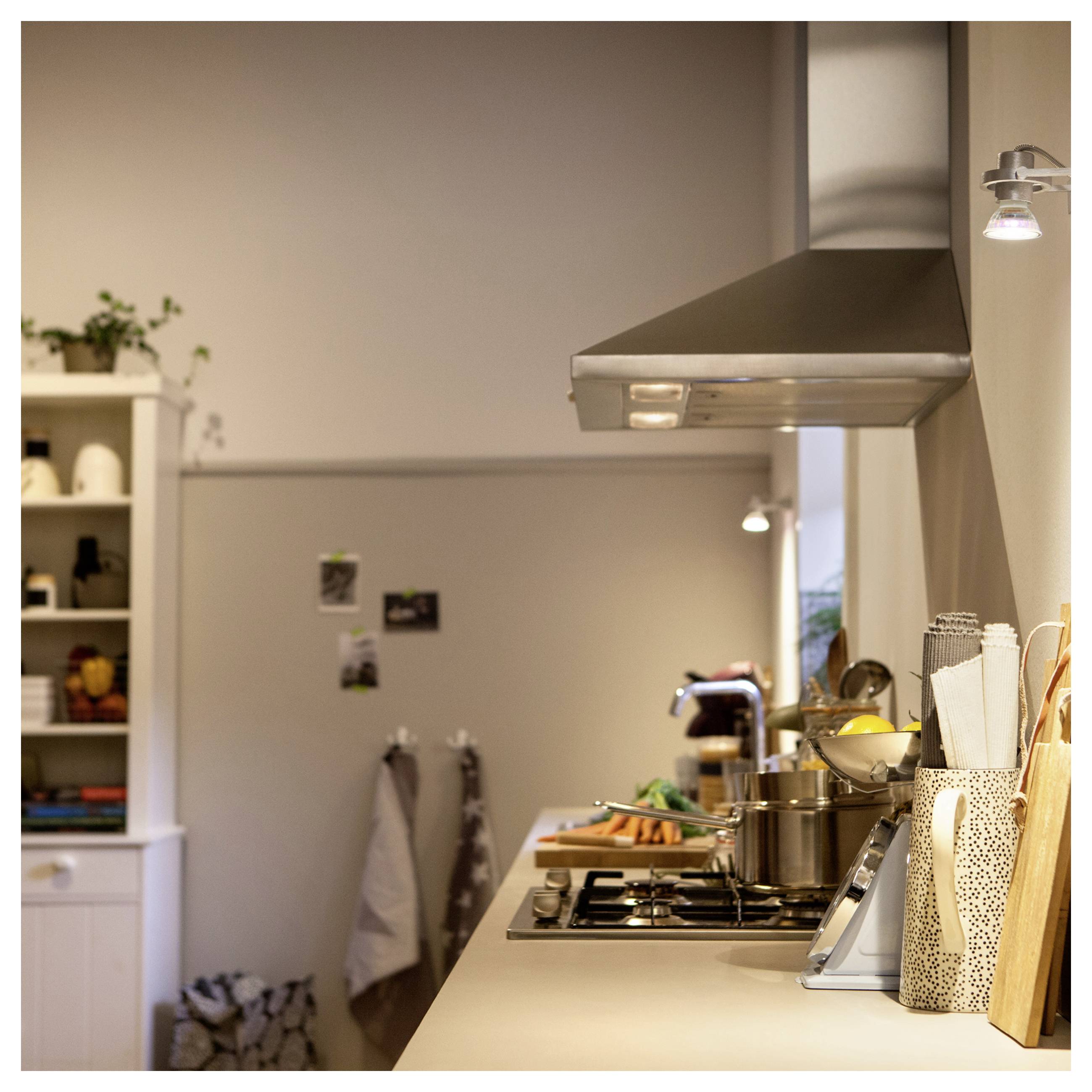 Un luminaire LED blanc suspendu de forme rectangulaire avec plusieurs petites lumières, suspendu au plafond par de fins câbles dans un décor minimaliste.