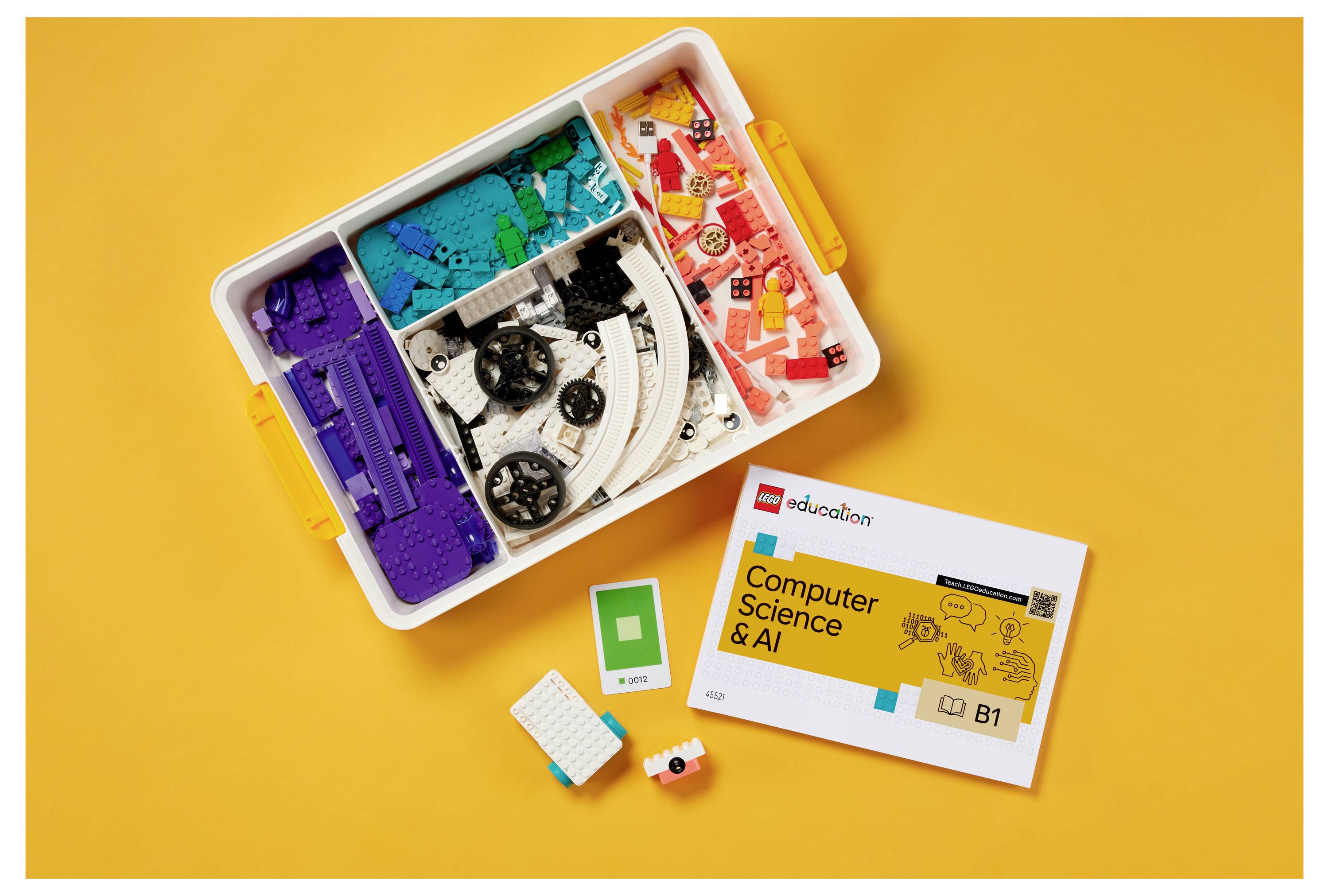 Un kit LEGO éducatif sur une surface orange contient des briques colorées et un livret intitulé « Informatique et IA », représentant des outils d'apprentissage.