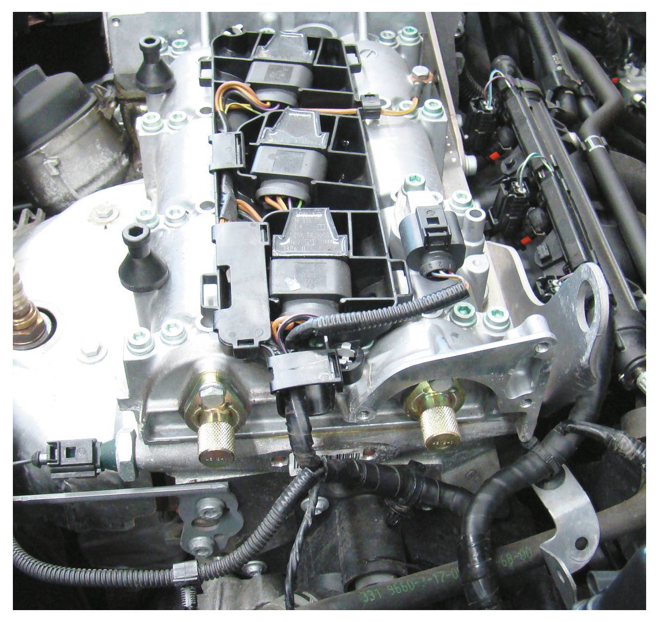 Gros plan d'un moteur automobile montrant des composants tels que le câblage, les bouchons et les tuyaux. L'accent est mis sur l'arrangement et la connectivité des pièces.